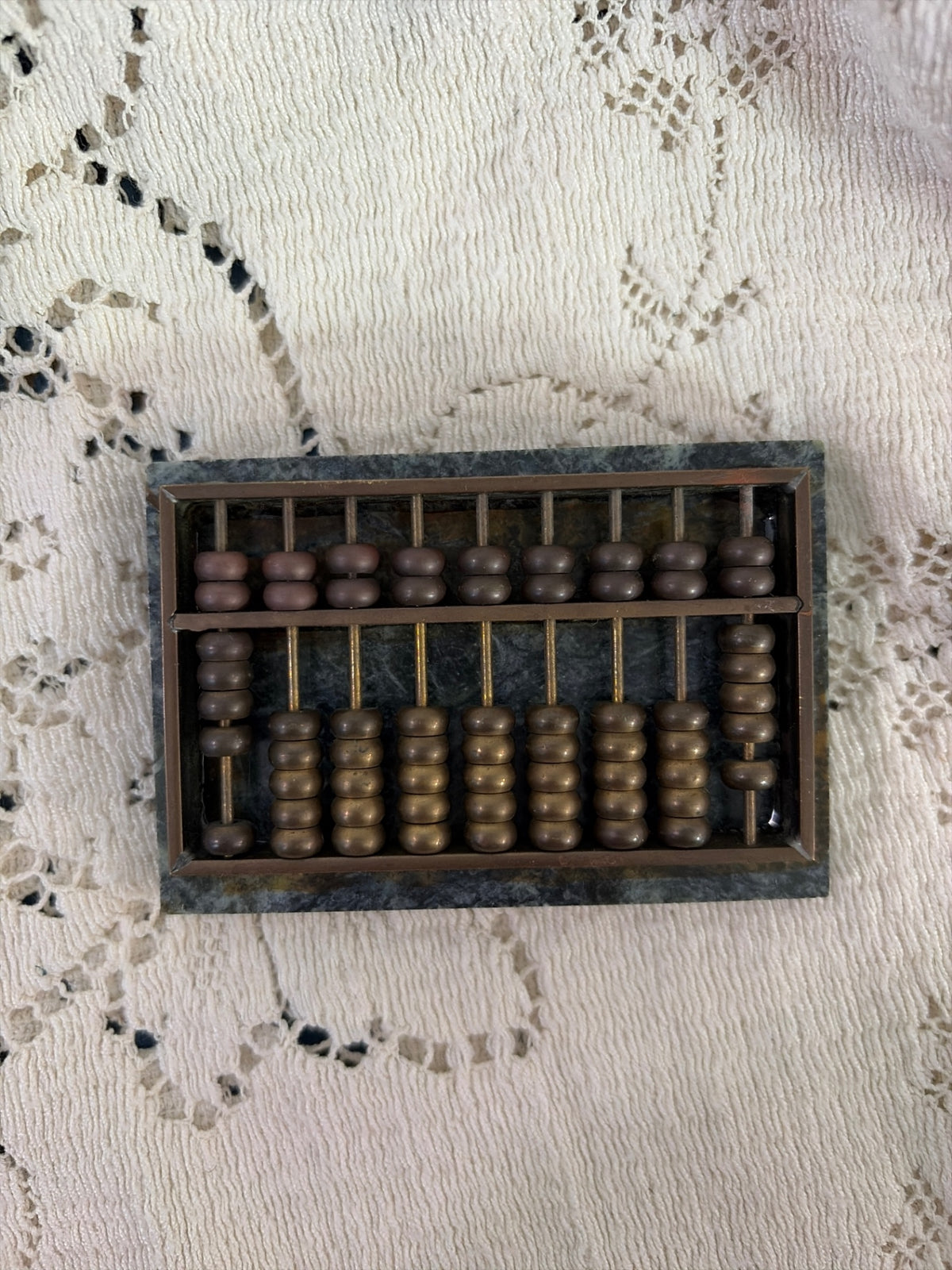 Brass abacus on green marble paperweight
