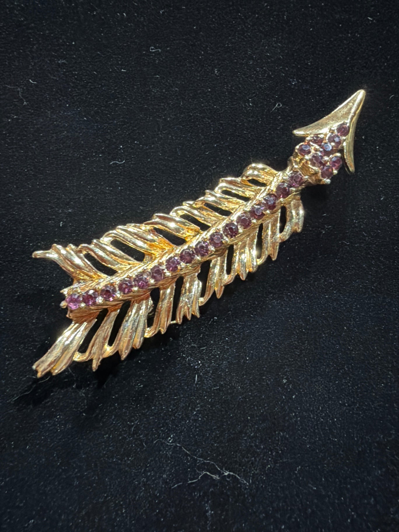 Gold tone feather brooch with purple rhinestones