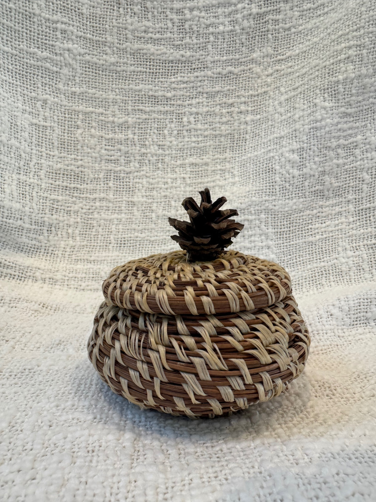 Pine needle basket with pinecone topped lid 