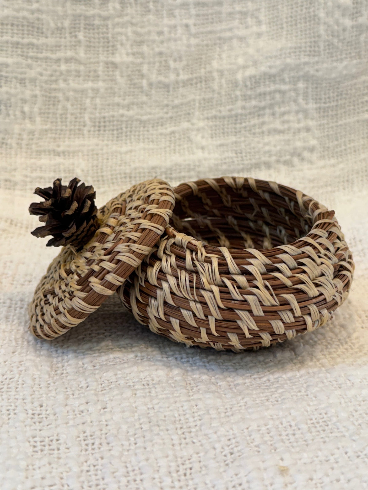 Pine needle basket with pinecone topped lid 